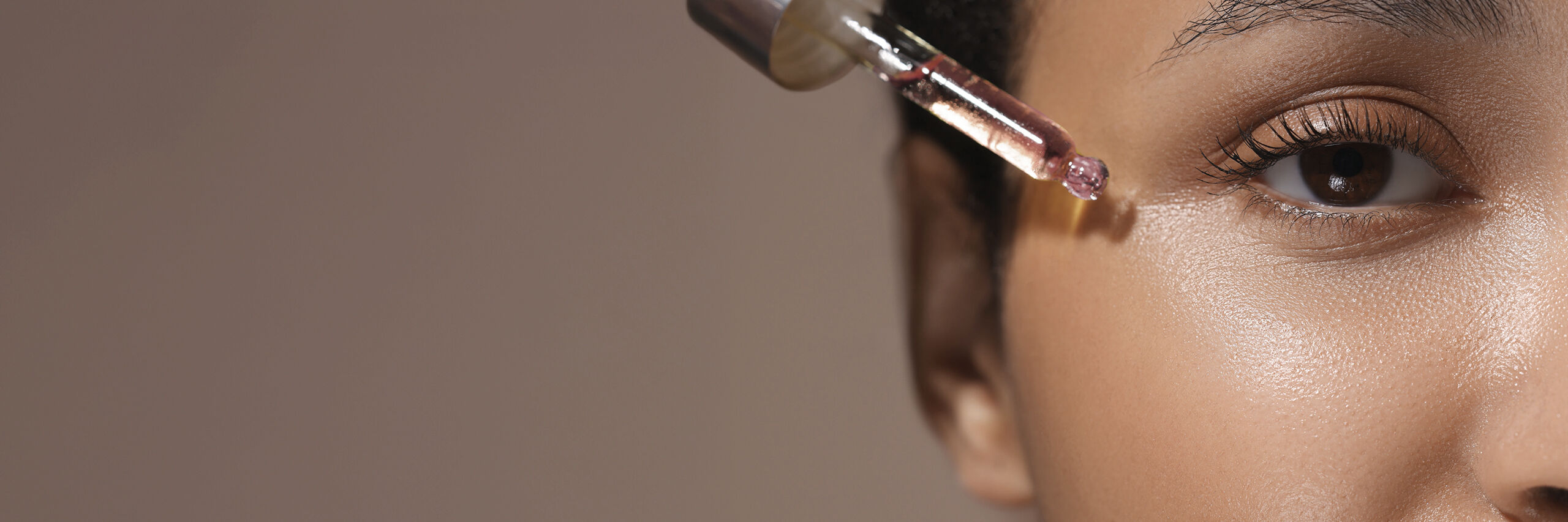 Eine Frau trägt sich mit einer Pipette ein Serum auf