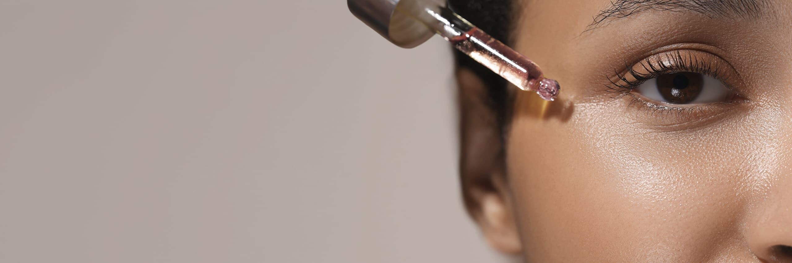 Eine Frau trägt sich mit einer Pipette ein Serum auf