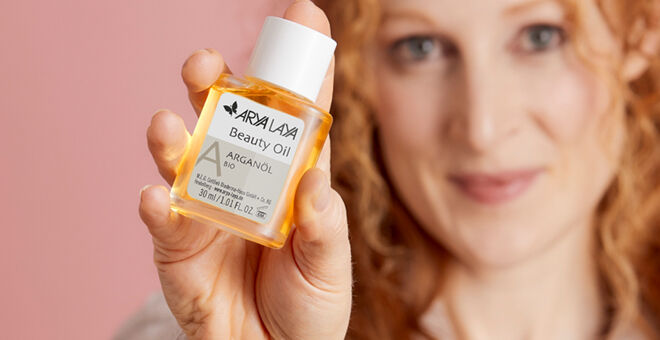 Eine Frau hält ein Beauty Oil in die Kamera