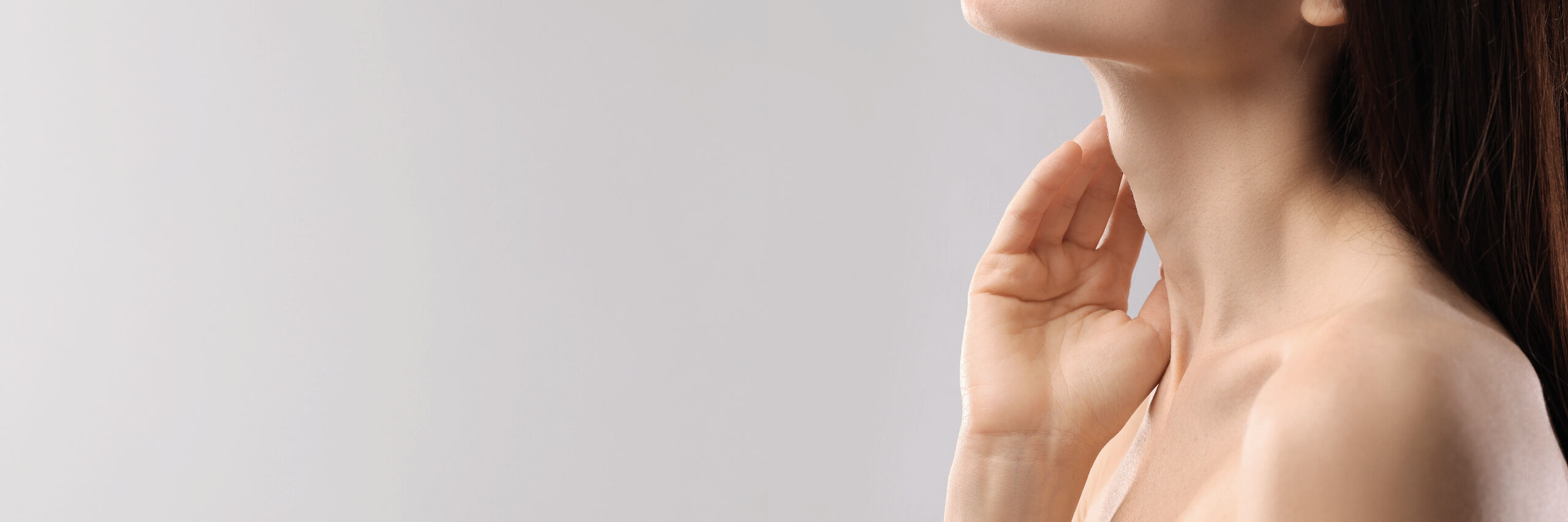 Eine Frau berührt mit Ihrer Hand ihr Décolleté