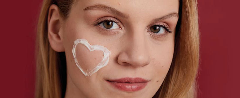 Frau mit einem mit Creme gemalten Herz auf der Wange