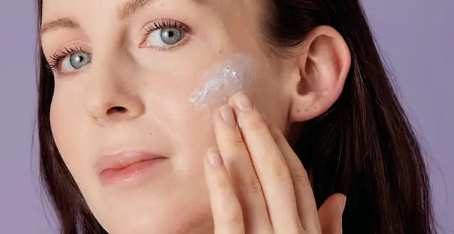 Frau trägt sich Creme auf der Wan