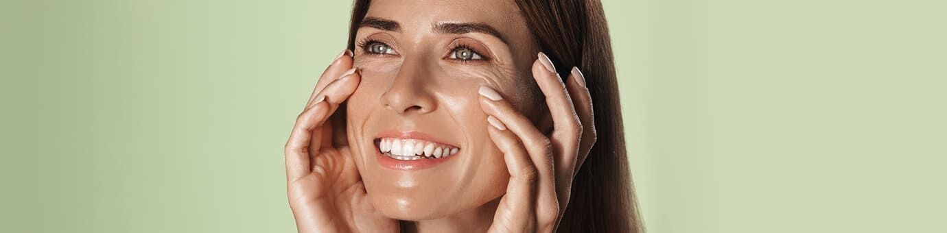 Junge Frau betastet Ihr Gesicht und strahlt dabei