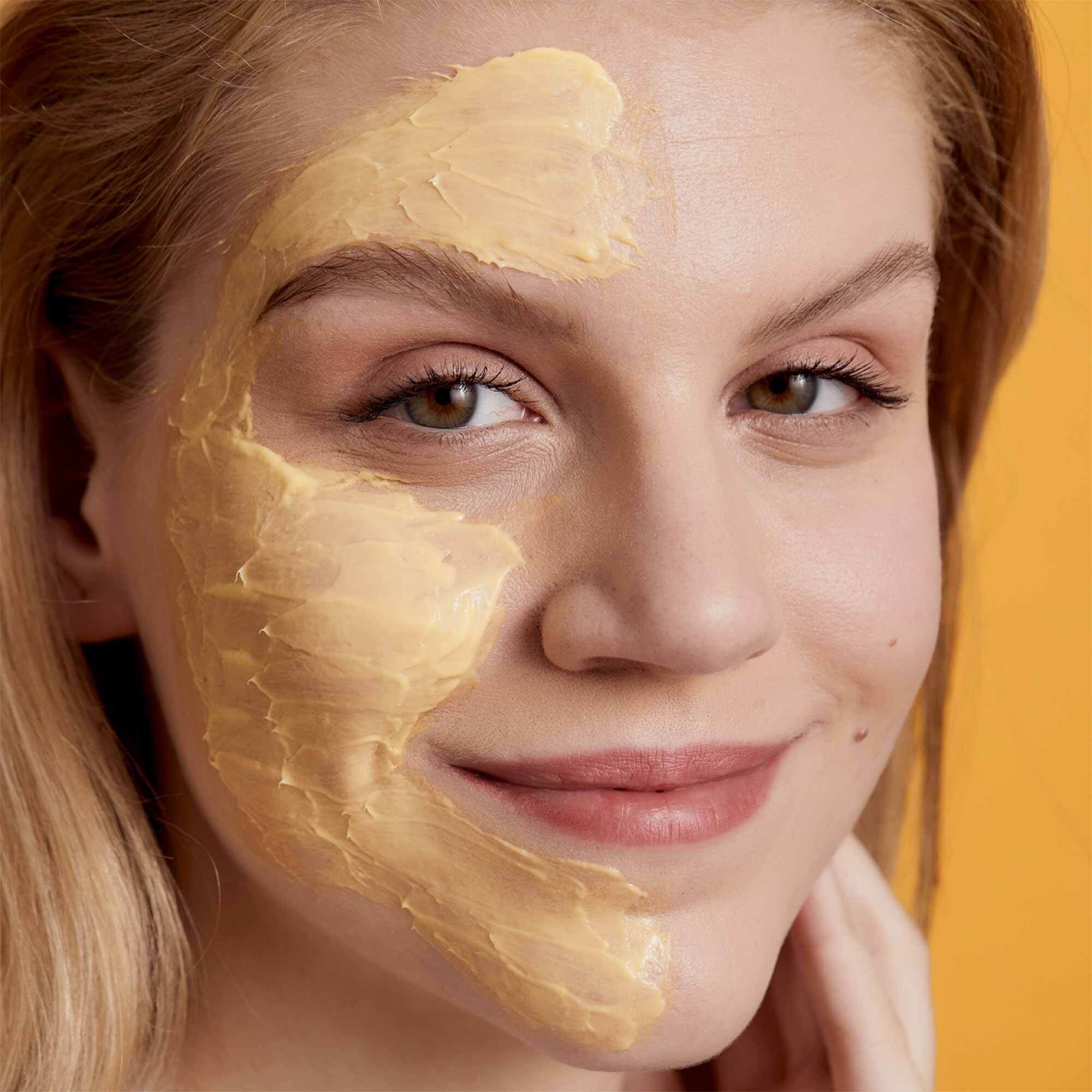 Eine Frau hat die Miracle Mask Vitamin Glow aufgetragen und lächelt in die Kamereá