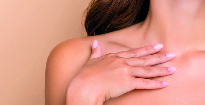 Eine Frau berührt mit Ihrer Hand ihr Décolleté