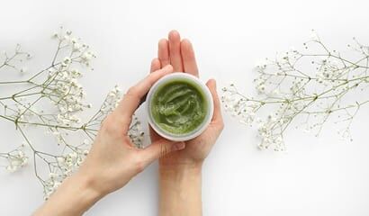 Frau präsentiert Tiegel  zermahlenen Pflanzen